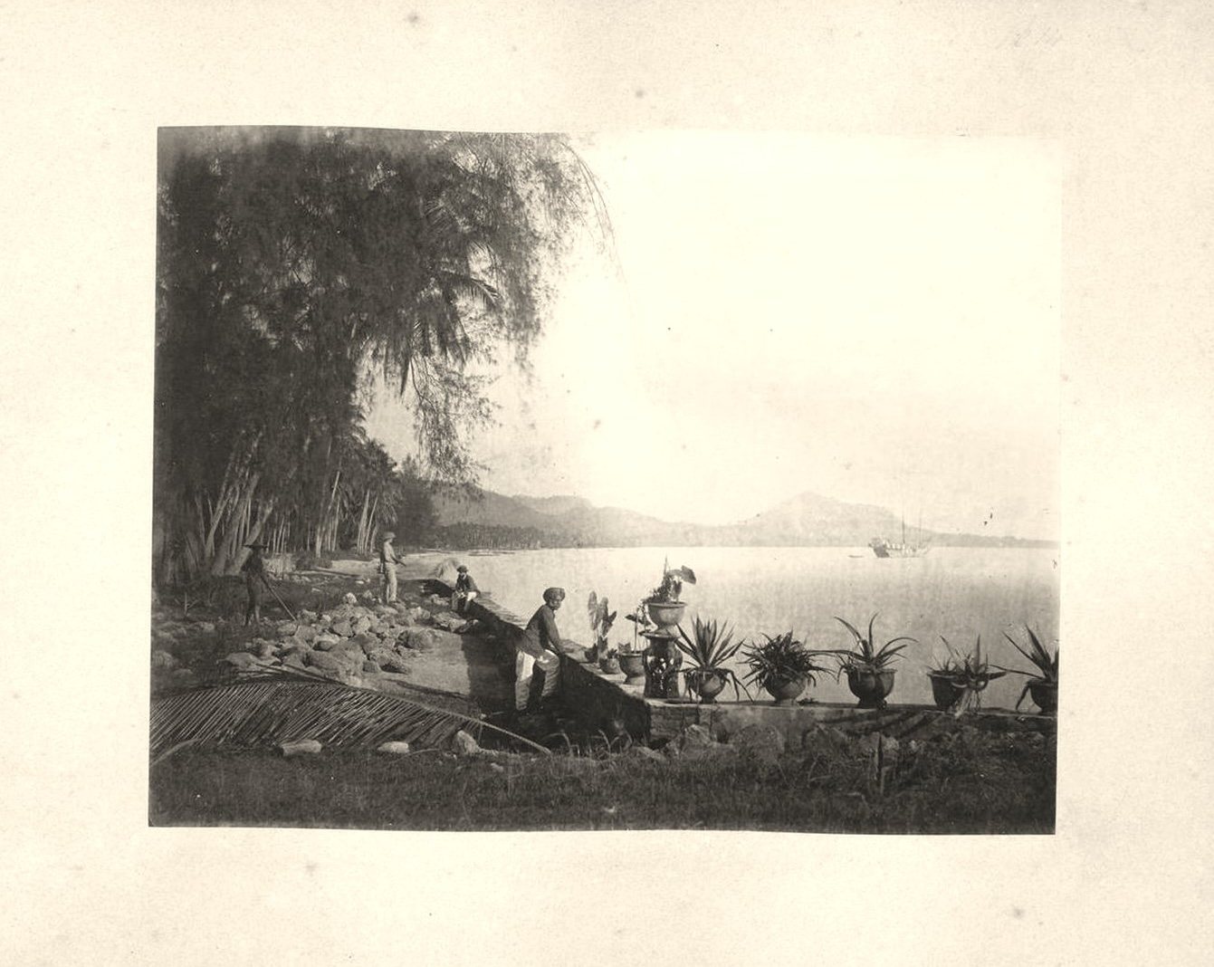 An album page: a bay seen from the shore, men working at the water's edge, a ship at anchor in the distance.