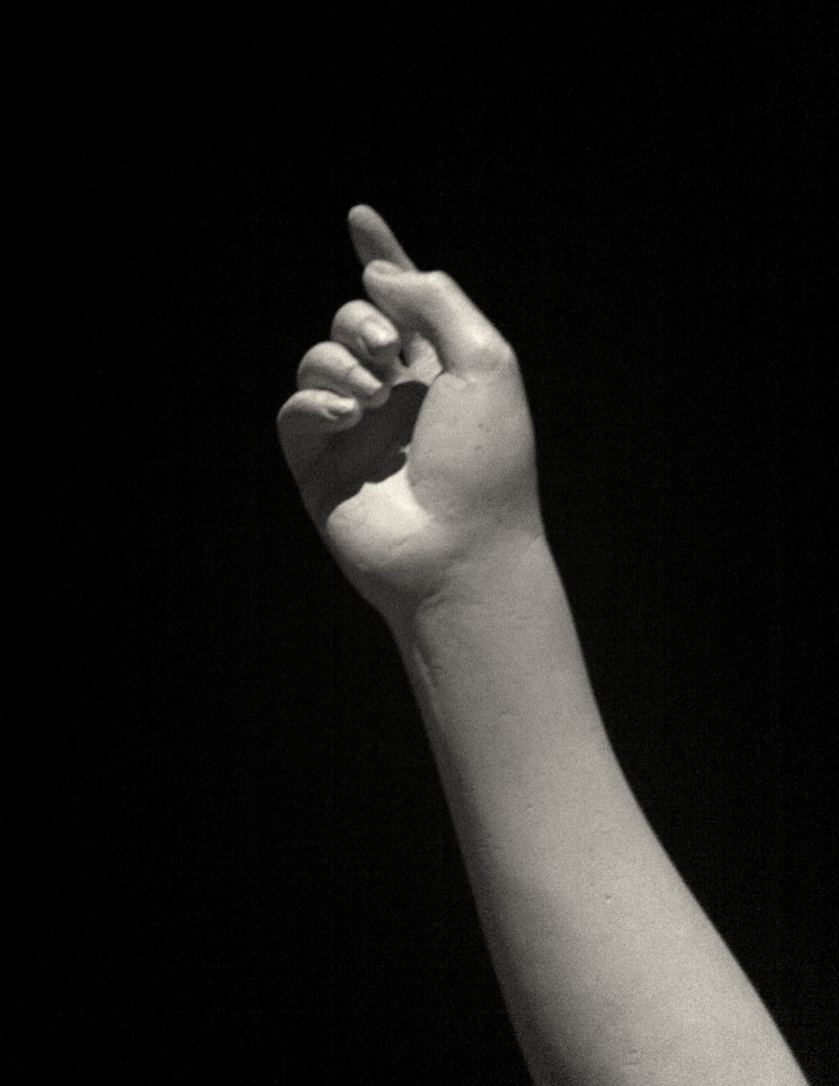 A raised arm and hand emerging from darkness.