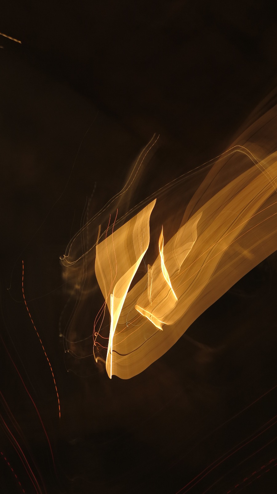Long-exposure photograph of golden light ribbons dissolving into darkness, Rome.