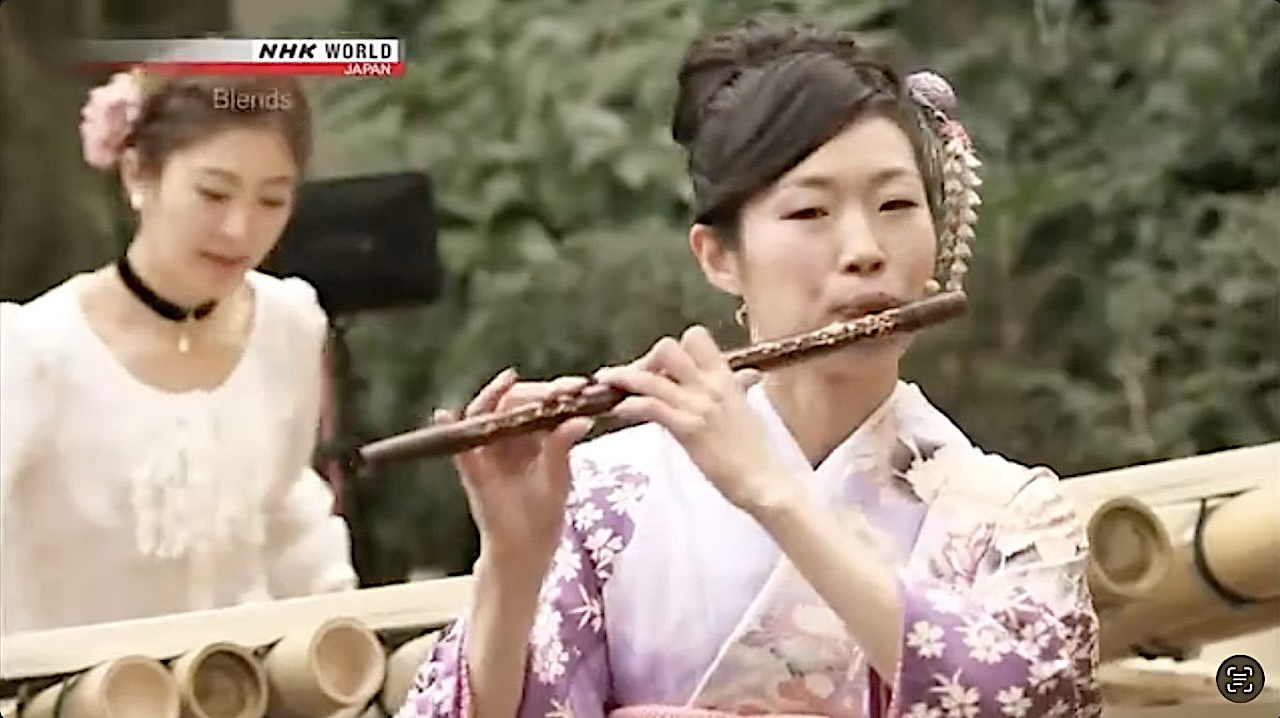 Sarah Akiyoshi playing shinobue on NHK World Blends, with another musician in the background.