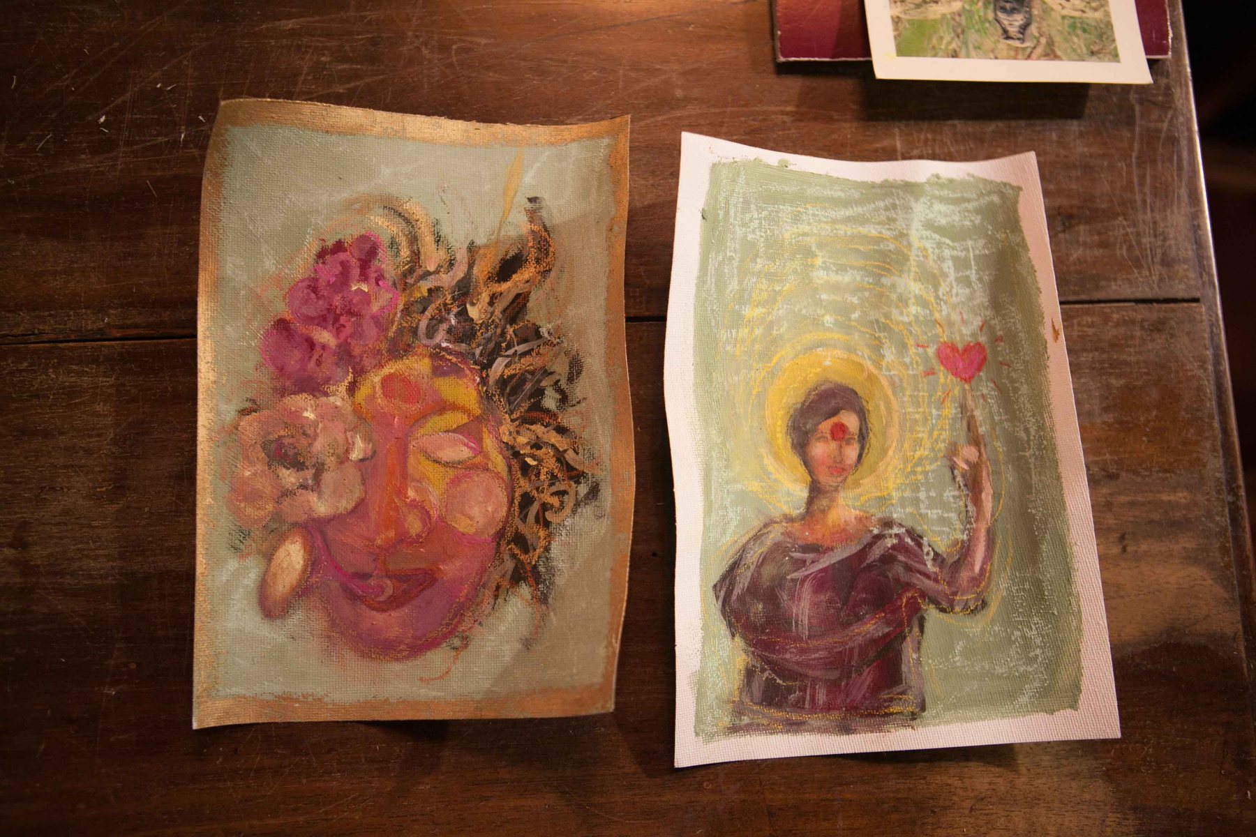 Two more small painted figures, a face surrounded by flowers, and a haloed figure holding a small red heart.